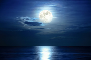 Super full moon and cloud in the blue sky above the ocean horizon at midnight, moonlight reflect...