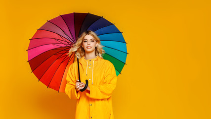 young happy emotional cheerful girl laughing  with   colorful  umbrella on colored yellow background