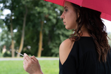 Brunette Girl smoking and sitting with red umbrella