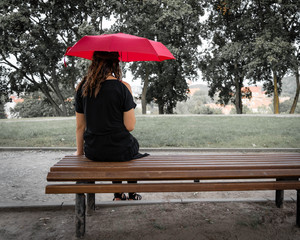 Lonely Gothic girl sitting with red umbrella