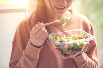 Closeup woman eating healthy food salad, focus on salad and fork