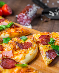 Pepperoni Pizza with Mozzarella cheese, salami, ham, Spices and Fresh basil. Italian pizza on wooden table background