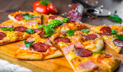 Pepperoni Pizza with Mozzarella cheese, salami, ham, Spices and Fresh basil. Italian pizza on wooden table background