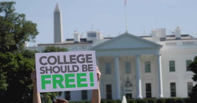 A man holds an COLLEGE SHOULD BE FREE protest sign in front of the White House on a sunny summer day.	