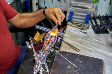 master blows glass on fire