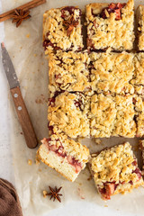 Apple pie bars with red berry jam, spices and crumble. Crumble cake. Light grey background.