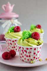Set of pistachio cupcakes decorated with fresh raspberries on neutral color background