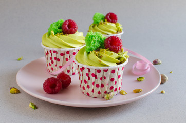 Set of pistachio cupcakes decorated with fresh raspberries on neutral color background