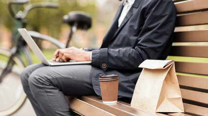 Businessman don't have time for snack, using laptop in park
