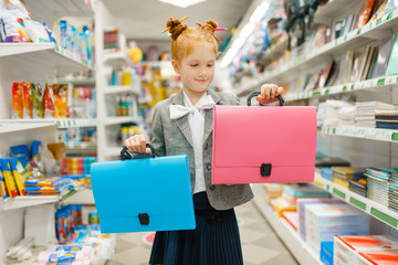 School girl with two folders in stationery store