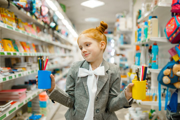 Schoolgirl holds glasses with pencils, stationery