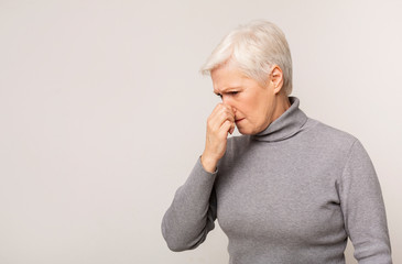 Senior woman closing nose because of bad smell