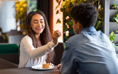 Young beautiful girl feeding her boyfriend cheesecake