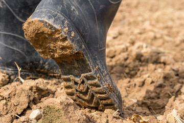 person walking with water boots with mud on the sole
