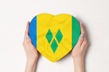 Flag of Saint Vincent and the Grenadines on a heart shaped box in a female hands. White background