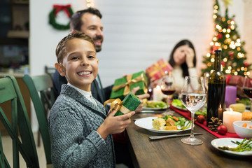 Excited Boy With Christmas Present At Dinner Party at Home