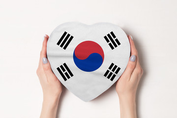 Flag of South Korea on a heart shaped box in a female hands. White background