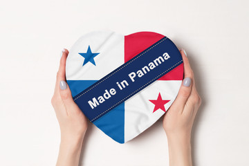 Inscription Made in Panama the flag of Panama . Female hands holding a heart shaped box. White background.
