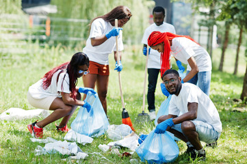 Group of happy african volunteers with garbage bags cleaning area in park. Africa volunteering,...