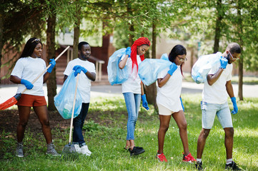 Group of happy african volunteers with garbage bags cleaning area in park. Africa volunteering,...