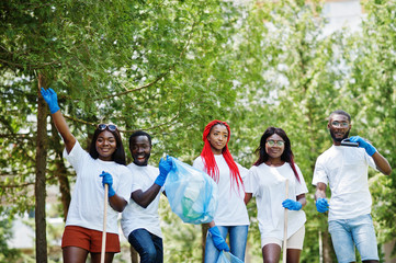 Group of happy african volunteers with garbage bags cleaning area in park. Africa volunteering, charity, people and ecology concept.