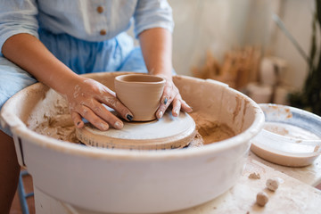 Obraz na płótnie Canvas Female master holds wet pot over the pottery wheel