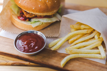 Fresh tasty burger and french fries on wooden table. french fries and bbq sauce on wood plate. street food burger and fried potatoes. Unhealthy food. fast food and unhealthy eating concept