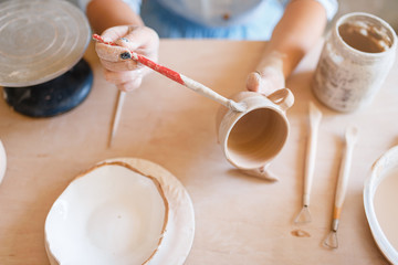 Female potter paints a pot, pottery workshop