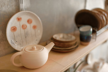 Obraz na płótnie Canvas Clay dishware on shelf in pottery workshop, nobody
