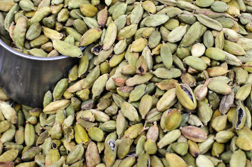 Cardamom seeds background with a steel measure cup at spice market