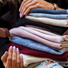 A very large assortment of hats in female hands. Fashion concept, stylist, knitted clothes.