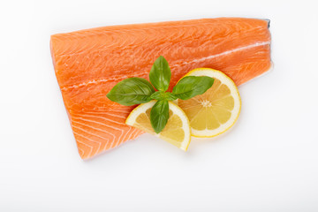 Fresh raw salmon fillets with herbs and lemon isolated on white background.