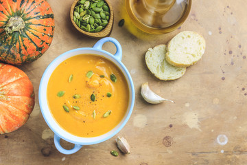 Pumpkin soup and organic pumpkins on rustic table.