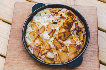 Potatoes baked with meat in the oven. Delicious dinner recipe. Potato pudding. Baked potato. Beef casserole. Potato gratin.Baked potatoes with eggs and chicken in a round bowl on a wooden table