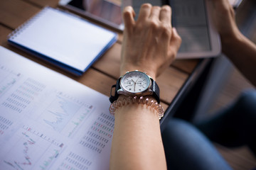 Women's hands with neat manicure and large wristwatch, work with gadgets, tablet, smartphone,...