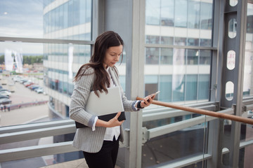 Young businesswoman with glasses and a phone in her hands. In the office or business center.