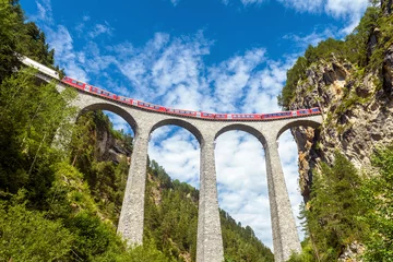 Papier Peint photo Viaduc de Landwasser Viaduc de Landwasser en Suisse. Le train rouge circule sur un pont de chemin de fer dans les montagnes alpines. Vue panoramique sur le célèbre chemin de fer suisse en été. Concept de voyage européen.
