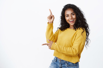 Cheerful carefree african-american woman in yellow sweater with curly haircut, smiling and laughing...