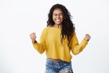 Confidence, business and wellbeing concept. Successful cheerful african american curly-haired girl fist pump and smiling, say yes close eyes from happiness, celebrating excellent news, winning