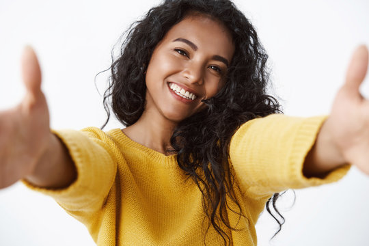 Close-up Shot Friendly, Carefree Good-looking African American Female With Curly Hairstyle, Stretch Hands Towards Camera In Hug, Wanna Cuddle You, Tilt Head And Smiling Cute, White Background