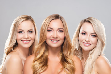 Studio portrait of young, beautiful and natural blond women over grey background. Close-up of smiling girls. Face lifting, plastic surgery, cosmetics and make-up.