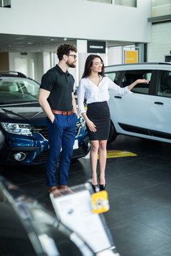 Two happy car sales consultants working inside vehicle showroom