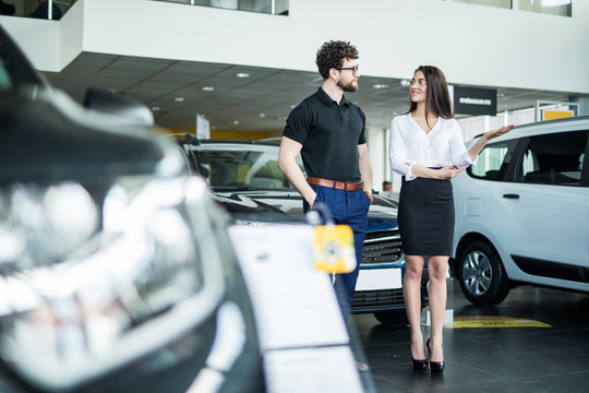 Professional salesperson selling cars at dealership to buyer in salon