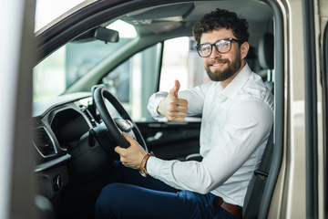 Thumbs up. Portrait of a happy businessman showing thumbs up sitting in his new car