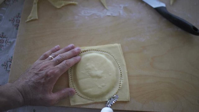 POV shot of cook cutting ravioli with a pastry cutter wheel. Cooking seadas, typical dessert of Sardinia, Italy.