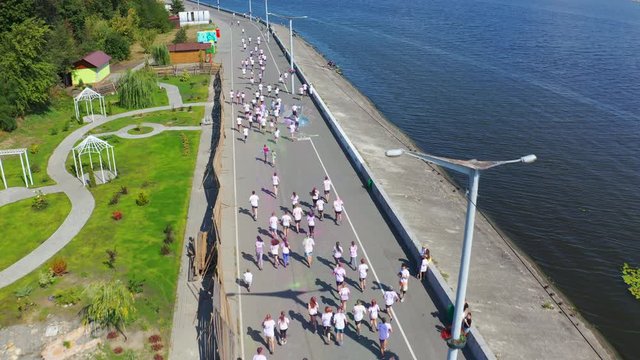 Participants of Holi run running in white T-shirts along the promenade. Aerial view footage 4k