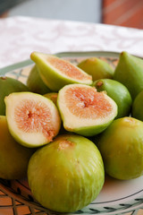 Ripe sweet figs. Figs fruit on a plate close up/macro. Healthy mediterranean fig fruit. Top view. Selective focus on the top figs slice in the bowl. Cut figs. Sliced fresh fruits.