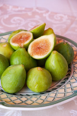 Ripe sweet figs. Figs fruit on a plate close up/macro. Healthy mediterranean fig fruit. Top view. Selective focus on the top figs slice in the bowl. Cut figs. Sliced fresh fruits.