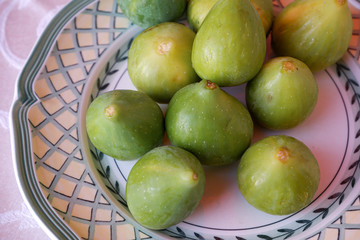 Ripe sweet figs. Figs fruit on a plate close up/macro. Healthy mediterranean fig fruit. Top view. Selective focus on the top figs slice in the bowl. Cut figs. Sliced fresh fruits.