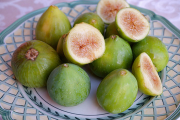 Ripe sweet figs. Figs fruit on a plate close up/macro. Healthy mediterranean fig fruit. Top view. Selective focus on the top figs slice in the bowl. Cut figs. Sliced fresh fruits.
